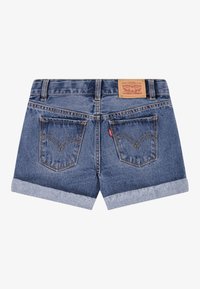 Shorts in denim di blu medio, con orli arrotolati, due tasche posteriori con dettagli di cucitura e un'etichetta in pelle con il marchio in vita.