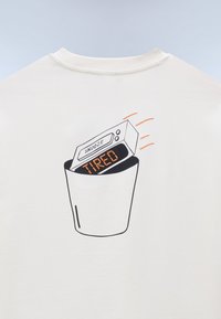 Ψηφιακό ξυπνητήρι που δείχνει τις λέξεις «ΚΟΥΡΑΣΜΕΝΟΣ» και «ΑΝΑΒΟΛΗ» να πετιούνται σε κάδο απορριμμάτων, τυπωμένο σε λευκό ύφασμα.