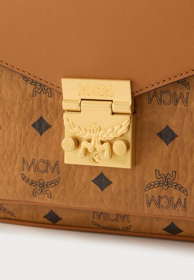 Sac à main en cuir fauve à finition texturée, doté de ferrures métalliques dorées et d'un logo embossé. Comprend un fermoir avec des détails décoratifs.