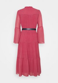 Robe midi rouge à petit motif blanc, manches longues évasées, jupe à volants et ceinture noire à la taille, vue de dos.