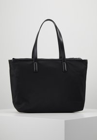 Svart tygväska med läderhandtag, med dragkedjestängning och en strukturerad, rektangulär form. Slät textur.