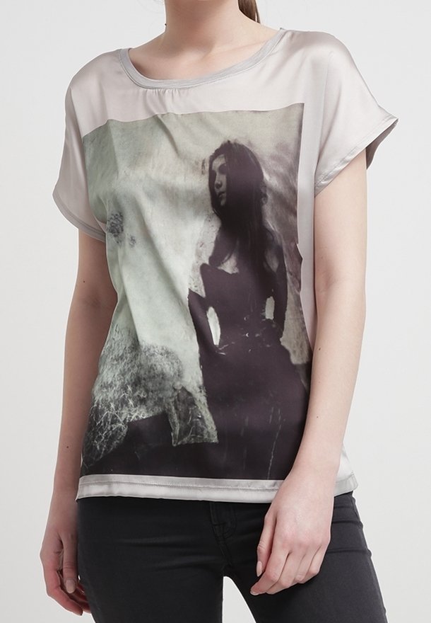 Camiseta de manga corta con un tejido semitransparente, que presenta una impresión fotográfica en blanco y negro. Cuello redondo, corte holgado, textura suave.