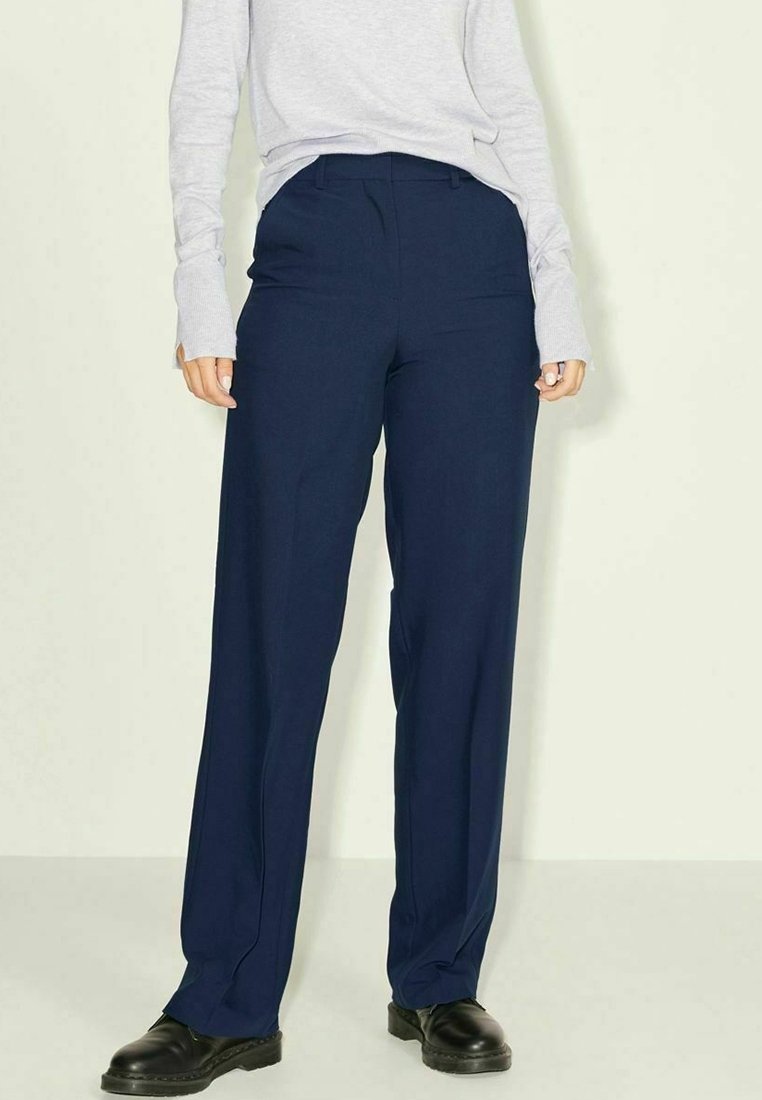 Marinblå byxor med vida ben av mjukt tyg, med slät textur och framvikta veck, kombinerade med en ljusgrå långärmad topp.