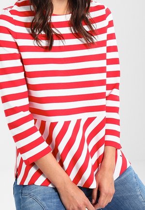 Rood-witte gestreepte peplum top met driekwartmouwen; horizontale strepen op het bovenste deel en diagonale strepen op de peplum.