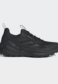 Scarpa da trail running Gore-Tex Terrex nera con suola texturizzata, tiranti sul tallone e sulla linguetta, e design a tre strisce sul lato.