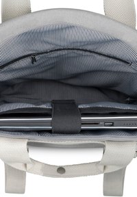 Szürke szövet laptop táska belseje csíkos bélésű, cipzáros zsebbel és egy fekete pánttal, amely rögzíti a laptopot. Tartalmazza a strapabíró fehér szövet fülöket.
