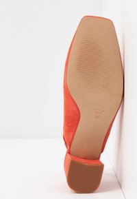 Chaussure à talons hauts en daim orange avec une forme effilée, dotée d'une semelle texturée et d'un talon épais. Marquée "Fabriqué en Espagne" et taille 37.