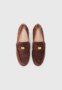 Pair of brown suede loafers with gold buckle accents and stitched detailing, shown from above on a plain background.