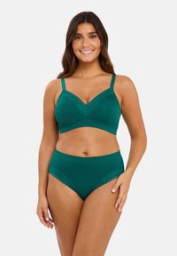 Conjunto de bralette verde con encaje y panties de talle alto. Tejido suave con textura acanalada. Tirantes ajustables y bordes decorativos en forma de ondas.