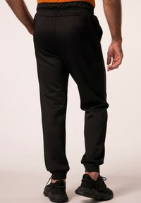 Joggers deportivos negros con cintura elástica, piernas ajustadas y puños acanalados. Tejido suave con un ligero brillo.