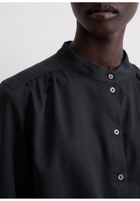 Czarna koszula z kołnierzykiem i zapinana na guziki z przodu, z delikatnymi marszczeniami na ramionach i gładką fakturą, wykonana z lekkiego materiału.