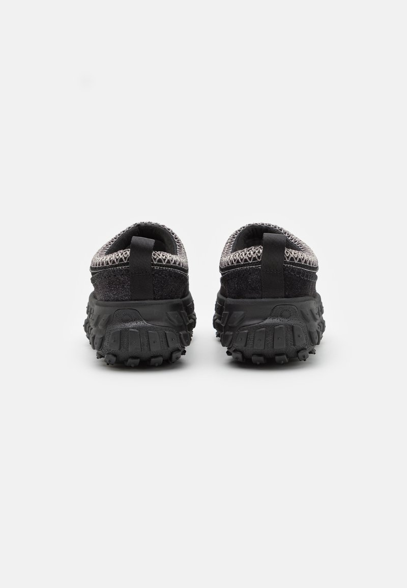 Schwarze Sportschuhe mit einem strukturierten Mesh-Obermaterial, ausgestattet mit einer gepolsterten Sohle und einer robusten Profilsohle für besseren Halt. Hinterer Zugriemen für ein einfaches Anziehen.