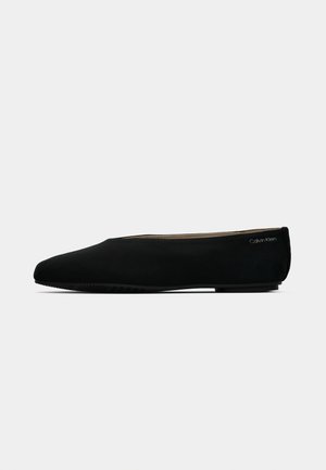 Black Calvin Klein flat shoe with a rounded toe, slip-on design, and subtle brand logo near the heel, shown in side profile.