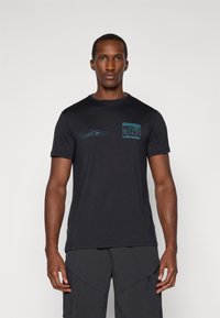 Camiseta negra de manga corta hecha de una tela suave, con gráficos de temática outdoor en azul claro en el frente y un detalle del logo en el bolsillo.