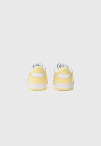 Le scarpe Nike gialle presentano un design in pelle liscia con accenti bianchi, forma arrotondata, colletto imbottito e suola in gomma texturizzata.