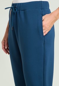 Türkise Jogginghosen mit einem Kordelzugbund, Seitentaschen und weicher Stofftextur. Sie verfügen über eine lockere Passform und modernes Design.