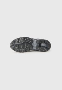 Black athletic shoe sole with a textured grip pattern and pronounced treads. Features a visible cushioned midsole and sleek design.