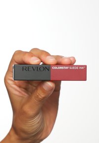 Produit à lèvres Revlon Colorstay Suede Ink dans un emballage rectangulaire, avec une combinaison de noir et de rouge vif et une marque en relief.
