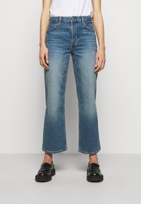 Light blue wide-leg jeans made of denim, featuring a high waist, clean cut, and slightly faded finish. Paired with black slip-on shoes.