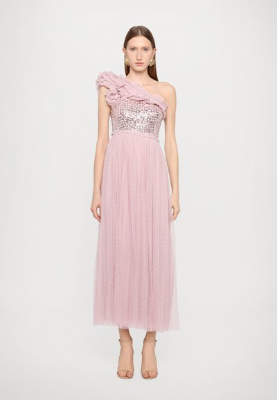 Vestido de tul rosa con un volante en un hombro, cuerpo de lentejuelas y una falda larga con puntos texturizados. Tacones nude lisos completan el look.