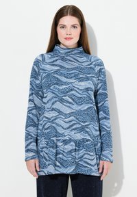 Maglia a maniche lunghe con collo alto in tonalità di blu, caratterizzata da un design a motivo ondulato. Tessuto morbido con orlo svasato e accenti testurizzati.