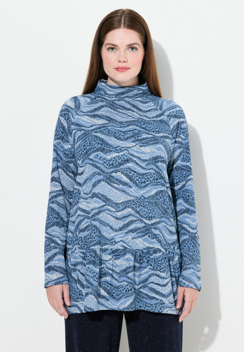 Maglia a maniche lunghe con collo alto in tonalità di blu, caratterizzata da un design a motivo ondulato. Tessuto morbido con orlo svasato e accenti testurizzati.
