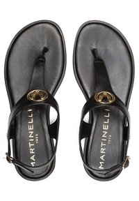 Sandales en cuir noir avec un design à l'orteil, ornées d'un accent circulaire doré et d'une bride de cheville ajustable. Texture lisse et style minimaliste.