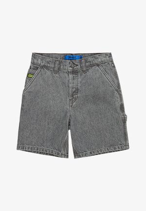 Szara koszulka, dżinsowe szorty z podwiniętym brzegiem oraz szare niskie trampki z białymi sznurowadłami i turkusowymi akcentami. Widoczne są szare skarpetki.