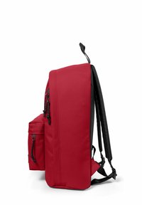 Sac à dos rouge avec des accents noirs, de forme rectangulaire, bretelles rembourrées, poche zippée extérieure, fabriqué dans un tissu durable.
