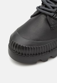 Μαύρο ανθεκτικό μποτάκι με παχύ υφασμάτινο πέλμα και στρογγυλή μύτη, διαθέτει γκρίζες και μαύρες ρίγες για κορδόνια και ενισχυμένες ραφές.