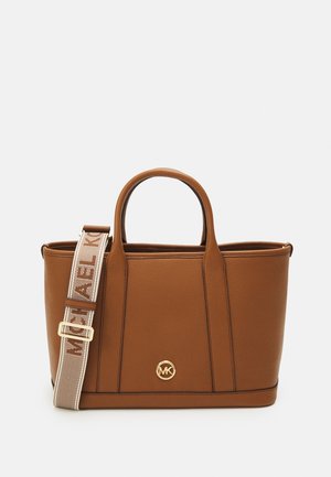 Sac fourre-tout en cuir marron avec poignées arrondies, bandoulière beige amovible avec marque, et logo doré circulaire MK au centre avant.