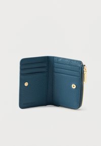 Sinihtävä vihreä nahkalompakko, jossa on vetoketjullinen suljin, useita korttipaikkoja, sileä pinta ja kullanväriset metallikoristeet.