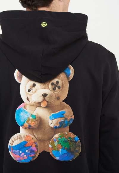 Μαύρο φούτερ με κουκούλα με γραφικό αρκουδάκι στην πλάτη που έχει μάτια από κουμπιά και πολύχρωμα πιτσιλίσματα μπογιάς στα πόδια και τις πατούσες.