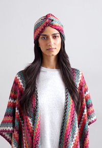 Banda de cap multicolor și șal cu modele, având designuri în zigzag în nuanțe de roz, turquoise și negru, fabricate dintr-un material ușor.