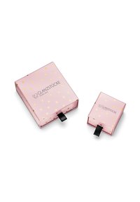 Divi rozā dāvanas iepakojumi ar zelta sirds rakstiem. Lielākajam iepakojumam ir melns vilkšanas cilpiņas; abi parāda zīmolu "Glanzstücke München."