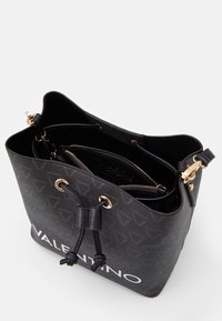 Black bucket bag with textured material and gold-tone hardware. Features a drawstring closure and an embossed logo on the front.