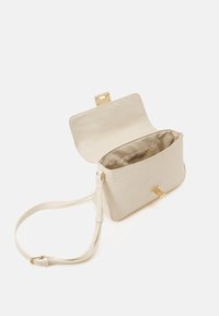 Beigová texturovaná kabelka s jemným geometrickým vzorem, zlatými detaily a nastavitelným ramenním popruhem. Otevřený vršek odhaluje hladký vnitřek.