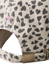 Casquette en tissu beige avec des motifs de cœurs noirs, un détail de cœur rose et une boucle de sangle réglable en laiton à l'arrière.