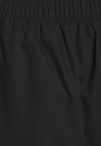 Čierna látka s hladkým povrchom, so zberovým pásom v páse a jemným ševom. Vhodná na bežné nosenie.