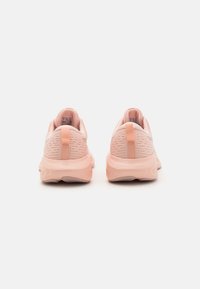 Light pink athletic shoes with a textured mesh upper, curved rubber sole, and a pull tab at the back for easy wear.