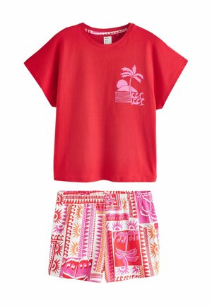 Červené tričko s krátkými rukávy s potiskem růžových palem a západu slunce, doplněné šortkami s elastickým pasem s červenými, růžovými a oranžovými geometrickými a slunečními vzory.