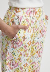 Pantalon coloré à motifs avec une base blanche, comportant des accents roses, jaunes et bleus ; comprend des poches latérales et une ceinture élastique.