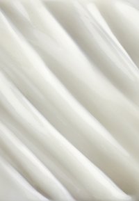 Glanzend wit keramisch oppervlak met gladde, golvende richels, die licht weerkaatsen. De textuur heeft subtiele variaties in glans en diepte.