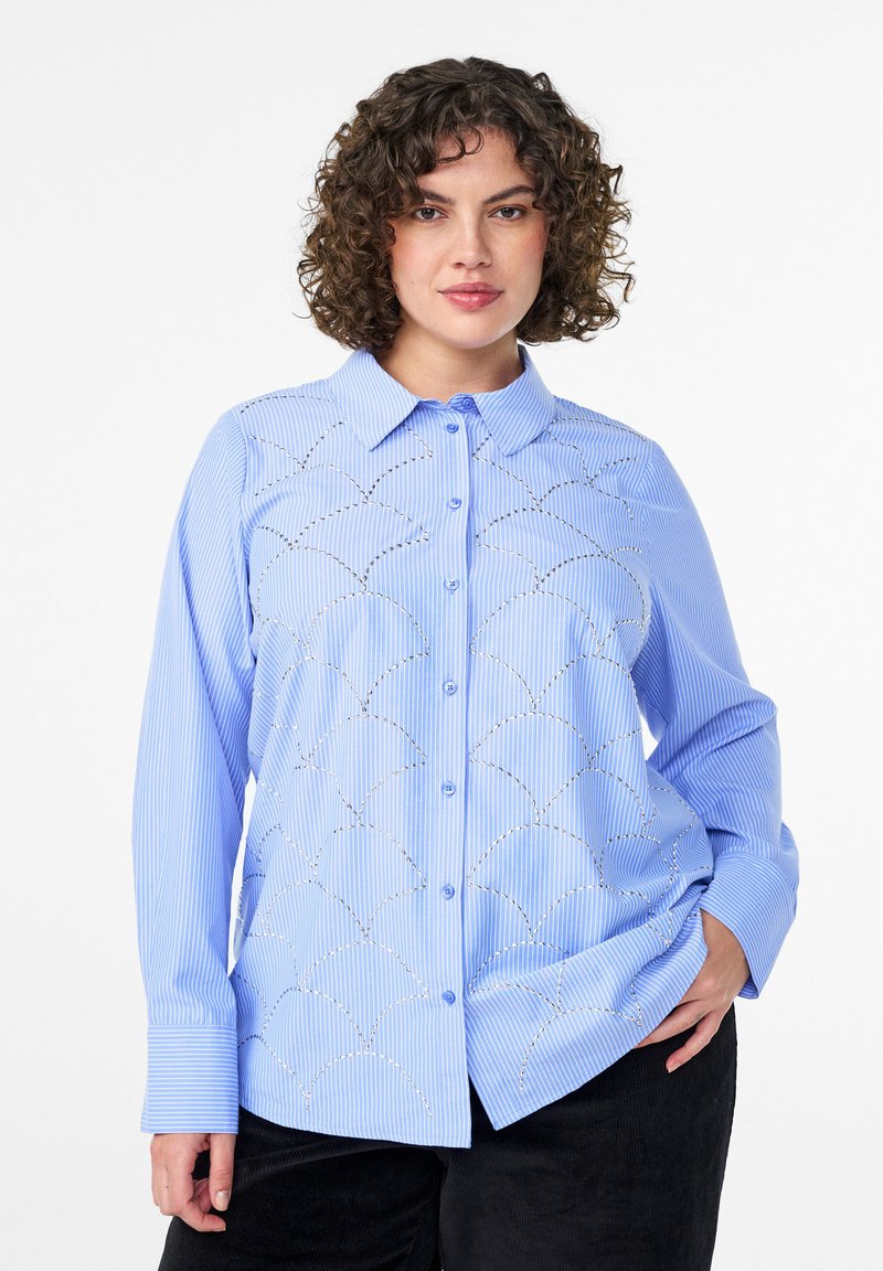 Light blue striped button-up shirt with long sleeves, featuring decorative scalloped stitching and metallic accents on the front.