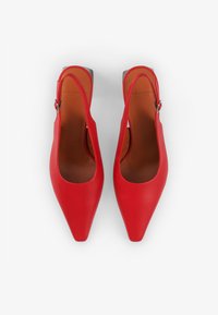 Red leather slingback shoes with a pointed toe, open sides, and a silver buckle detail on the strap. Smooth texture and sleek design.