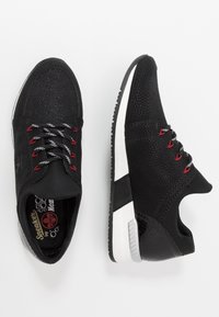 Baskets noires avec une tige texturée, une semelle blanche contrastante et des accents rouges. Comprend des lacets à motifs et un design à bout arrondi.