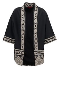 Sort åben-front kimonojakke med beige geometrisk mønstret trim på krave, ærmer og kant, som viser traditionelt vævet design.