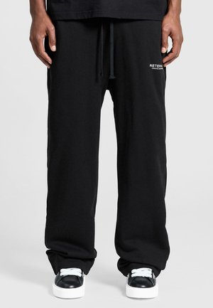 Black sweatpants made of cotton, featuring a straight leg design, adjustable waistband, and branding detail on the left side.