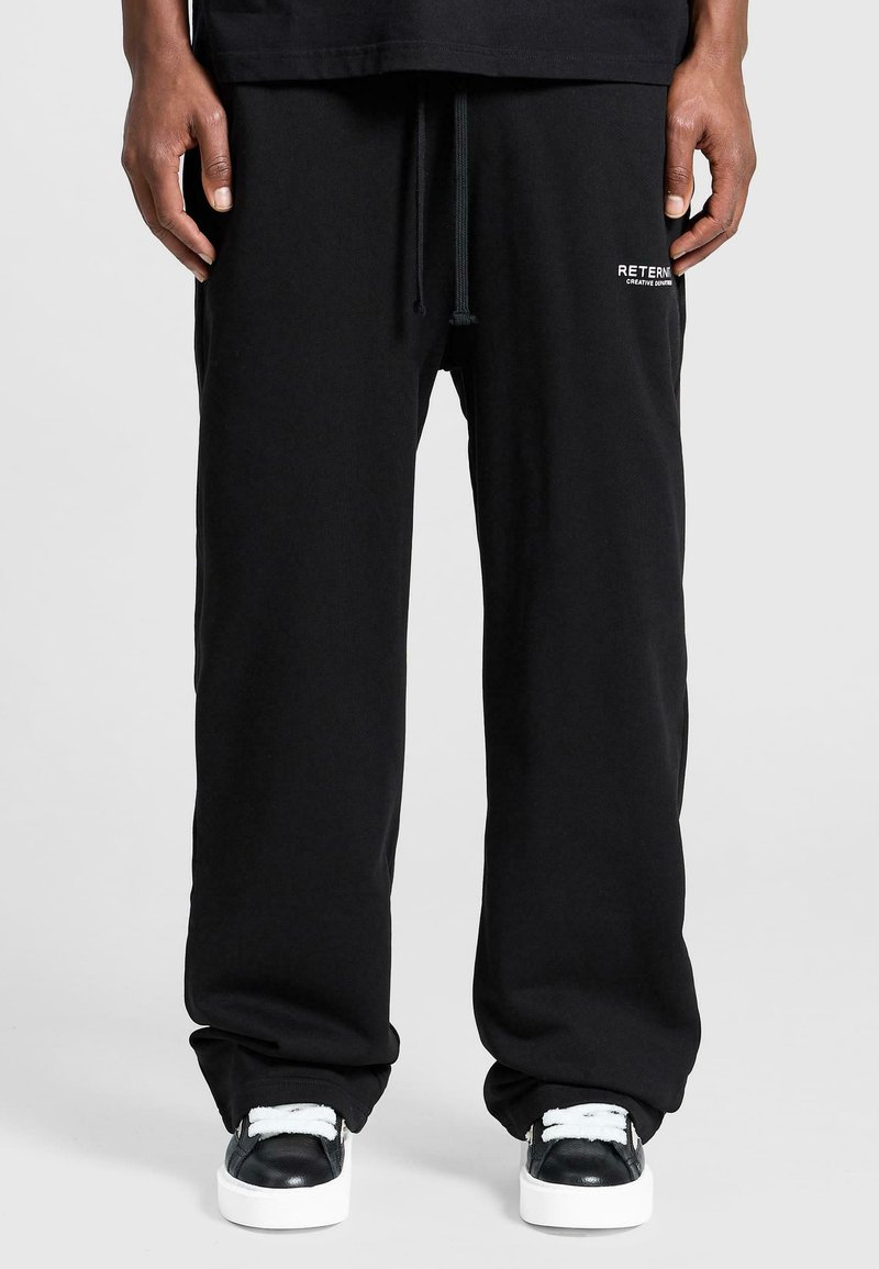 Black sweatpants made of cotton, featuring a straight leg design, adjustable waistband, and branding detail on the left side.