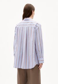 Lichtblauw gestreepte shirt met lange mouwen, rugplooien en knoopmanchetten. De strepen hebben oranje en marineblauwe accenten. Ontworpen voor een losse pasvorm.